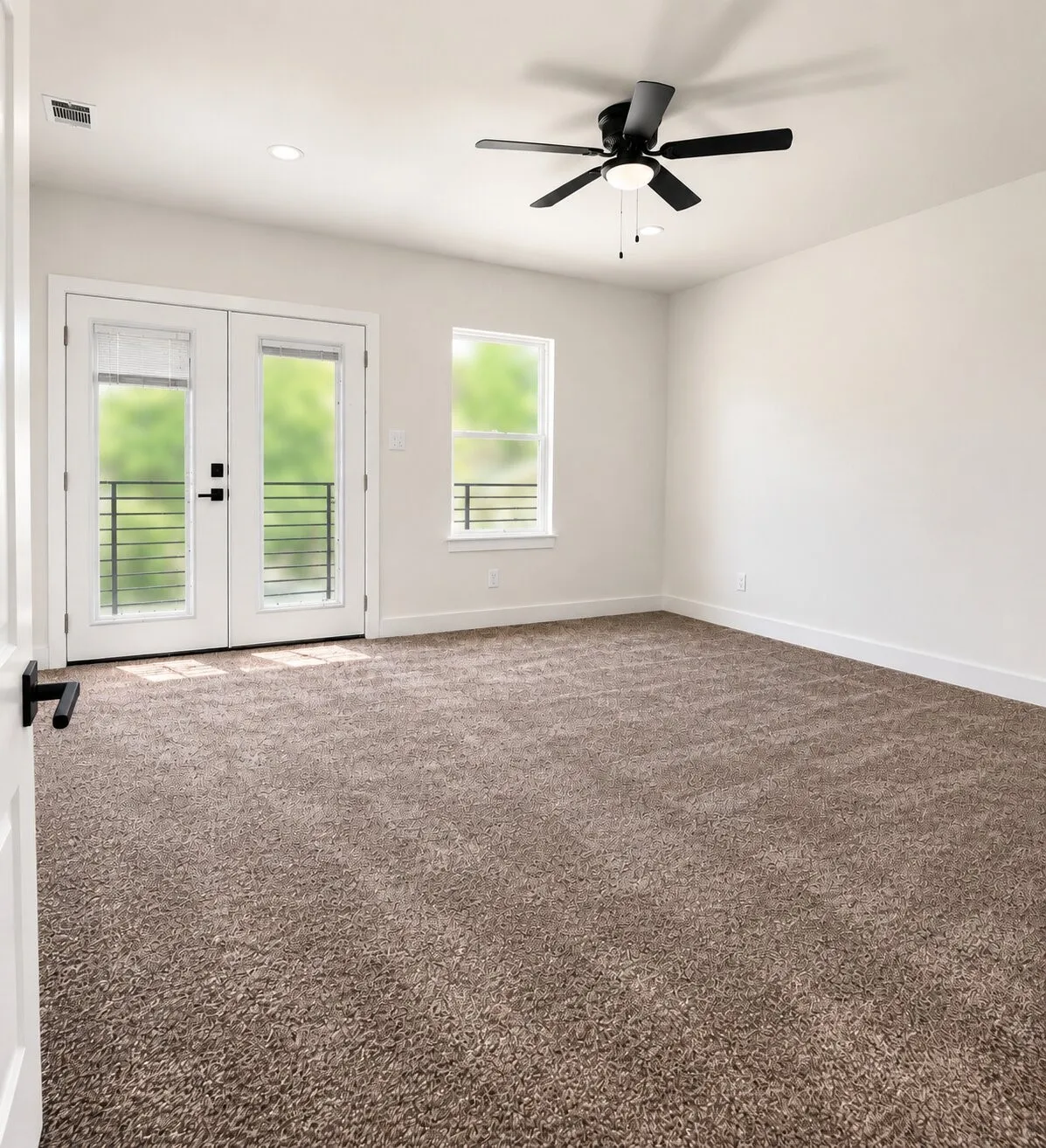 Spacious room featuring neutral carpeting, double glass-paned doors with black hardware, a ceiling fan, and recessed lighting