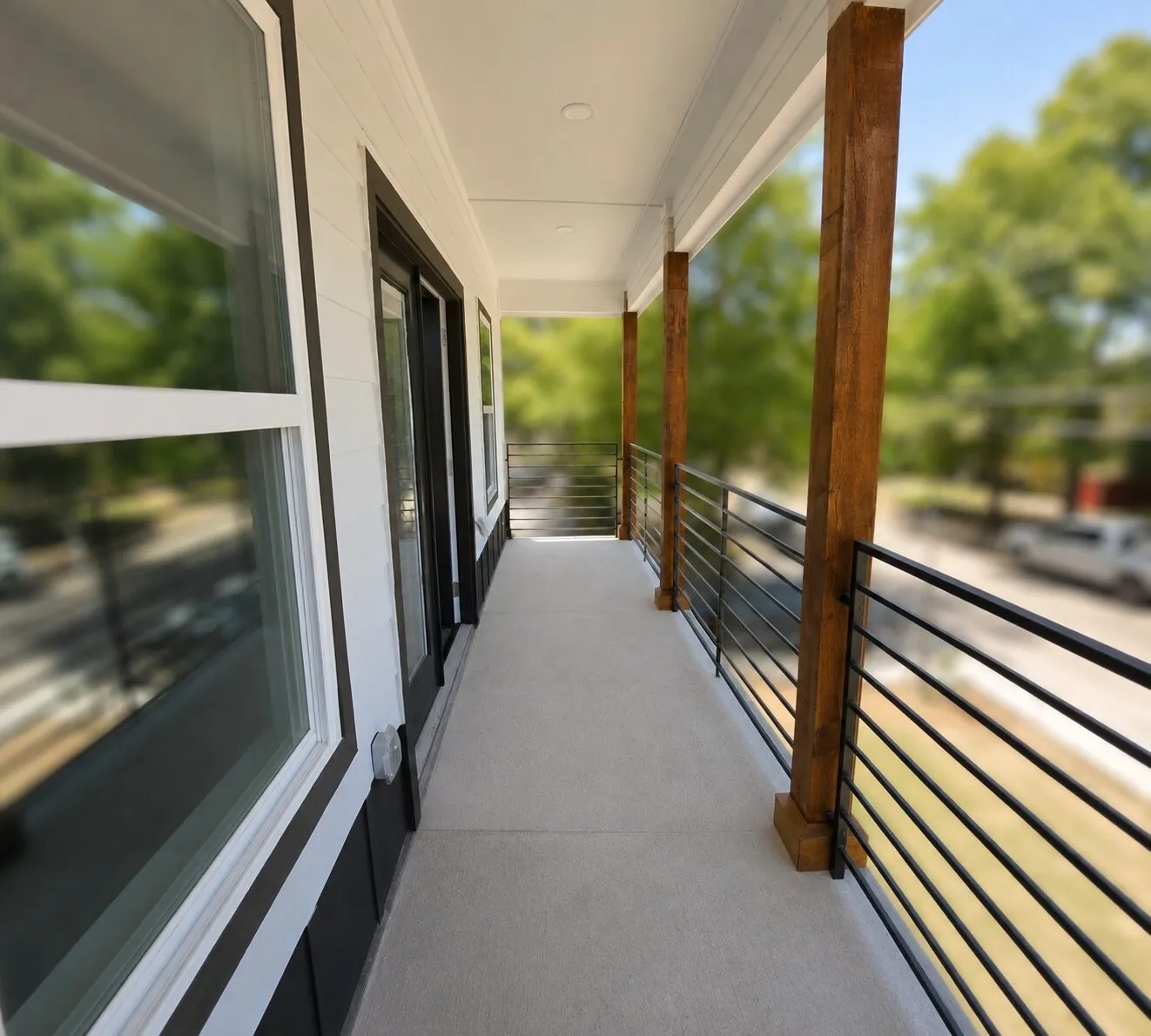 Exterior balcony featuring a concrete floor, horizontal rod railing, and natural wood support columns