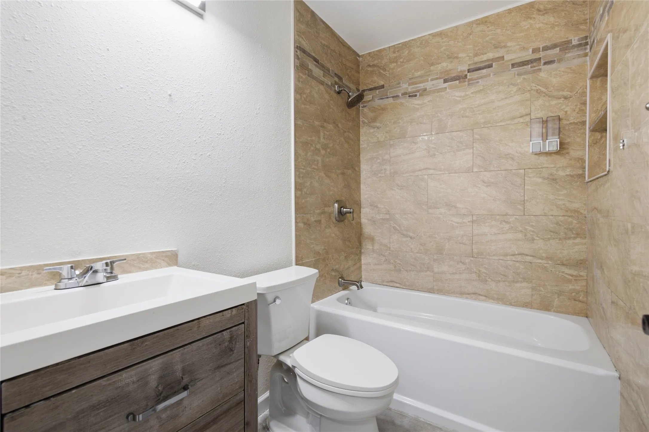 Bathroom featuring a white vanity with wood-finish cabinetry, a white rectangular undermount sink, and a chrome faucet