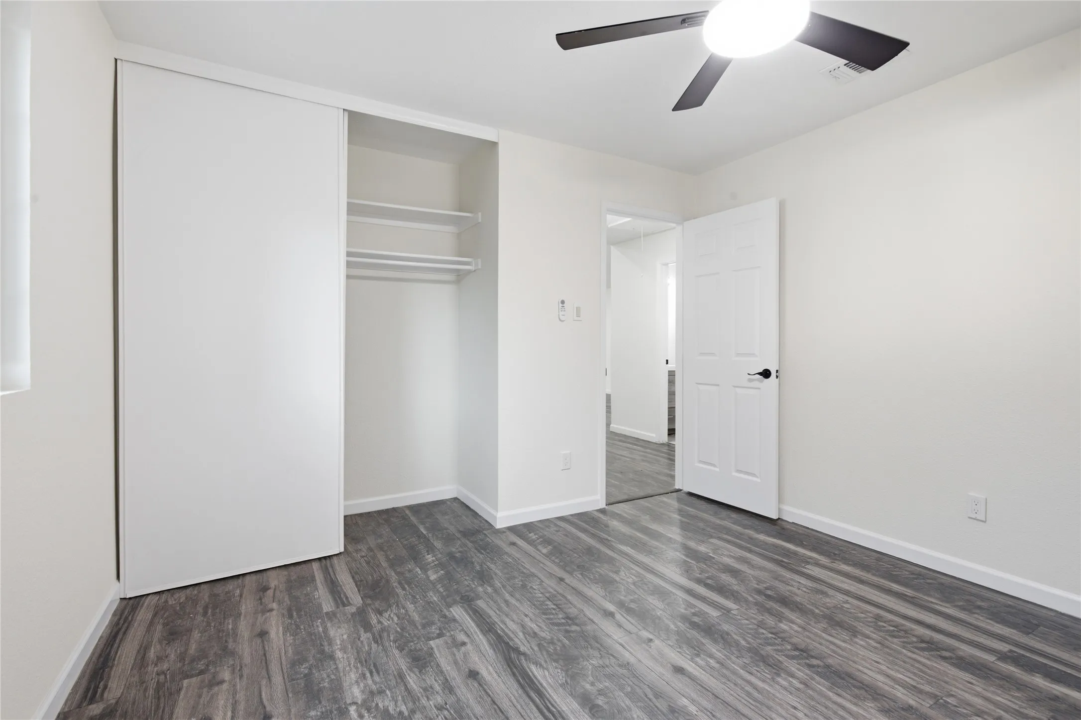 Wood-finish flooring with white walls and a white paneled door