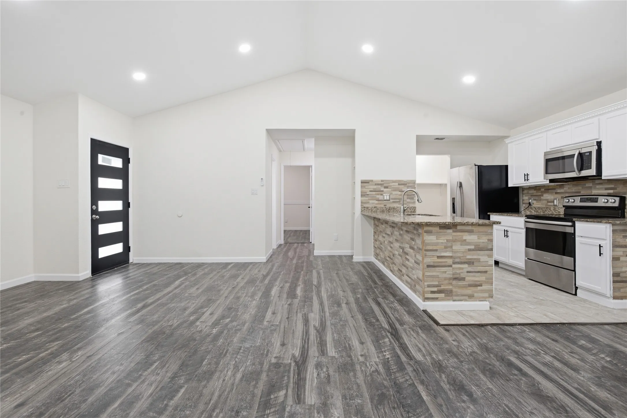Vaulted ceilings enhance the open-concept design featuring wood-finish flooring