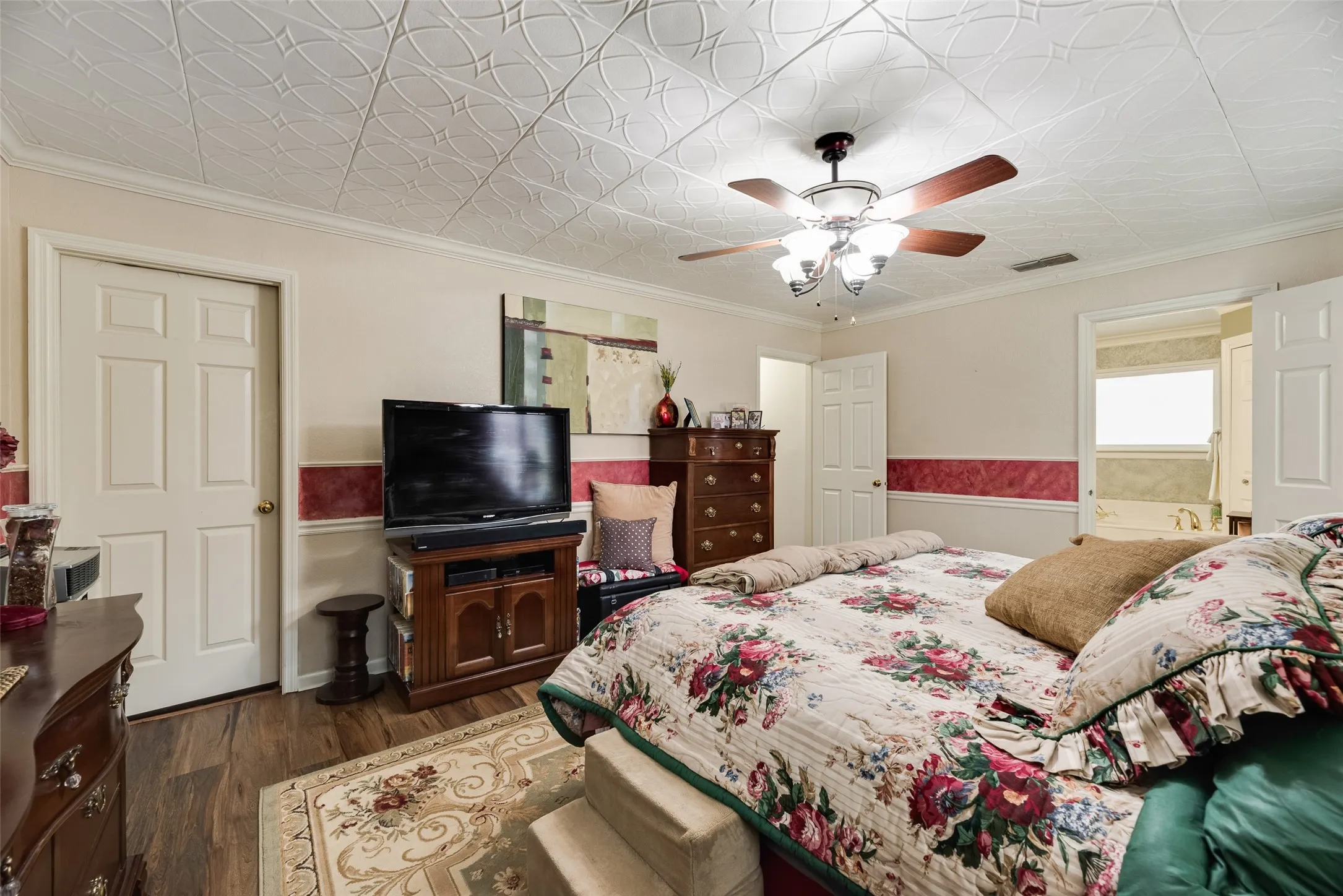 Decorative ceiling with a ceiling fan, crown molding, wood-finish flooring, and white paneled doors