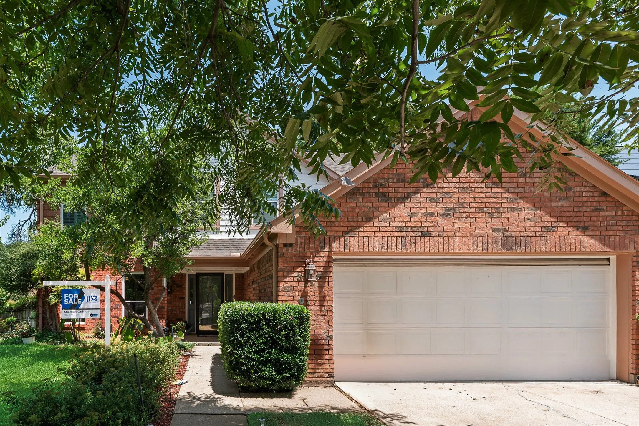 Brick exterior with a peaked roofline, a two-car garage, and a concrete driveway