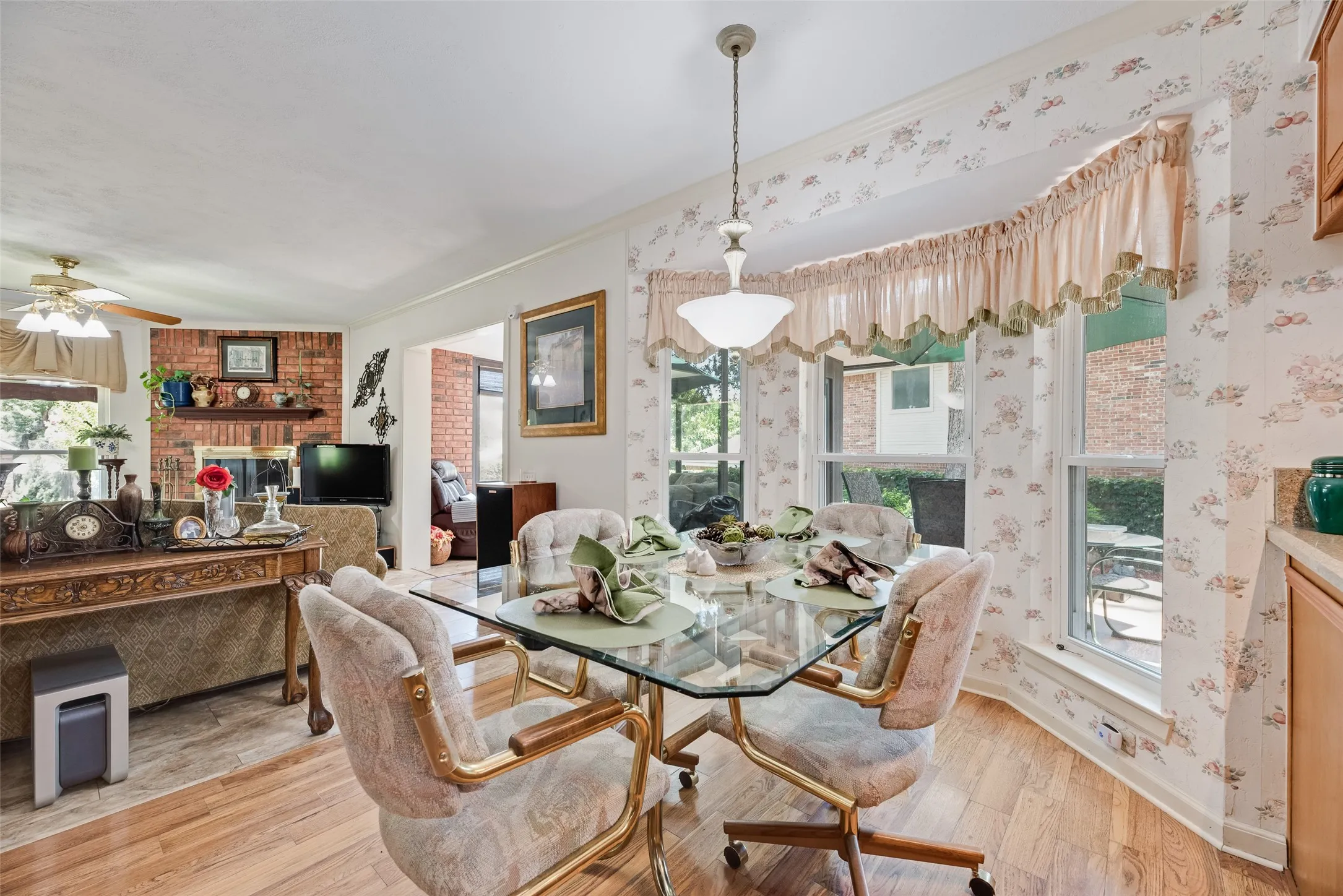 Wood-finish flooring, bay window, tray ceiling, recessed lighting, and brick fireplace