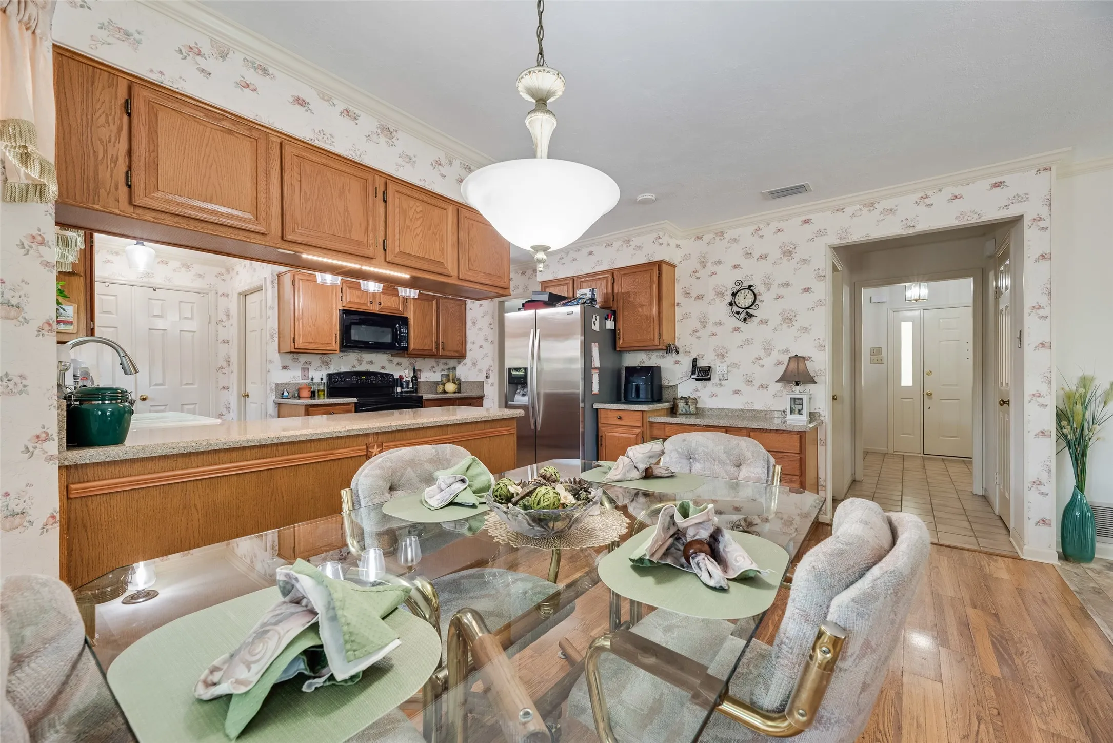 Kitchen featuring wood cabinetry, stainless steel refrigerator, black microwave, and black electric range