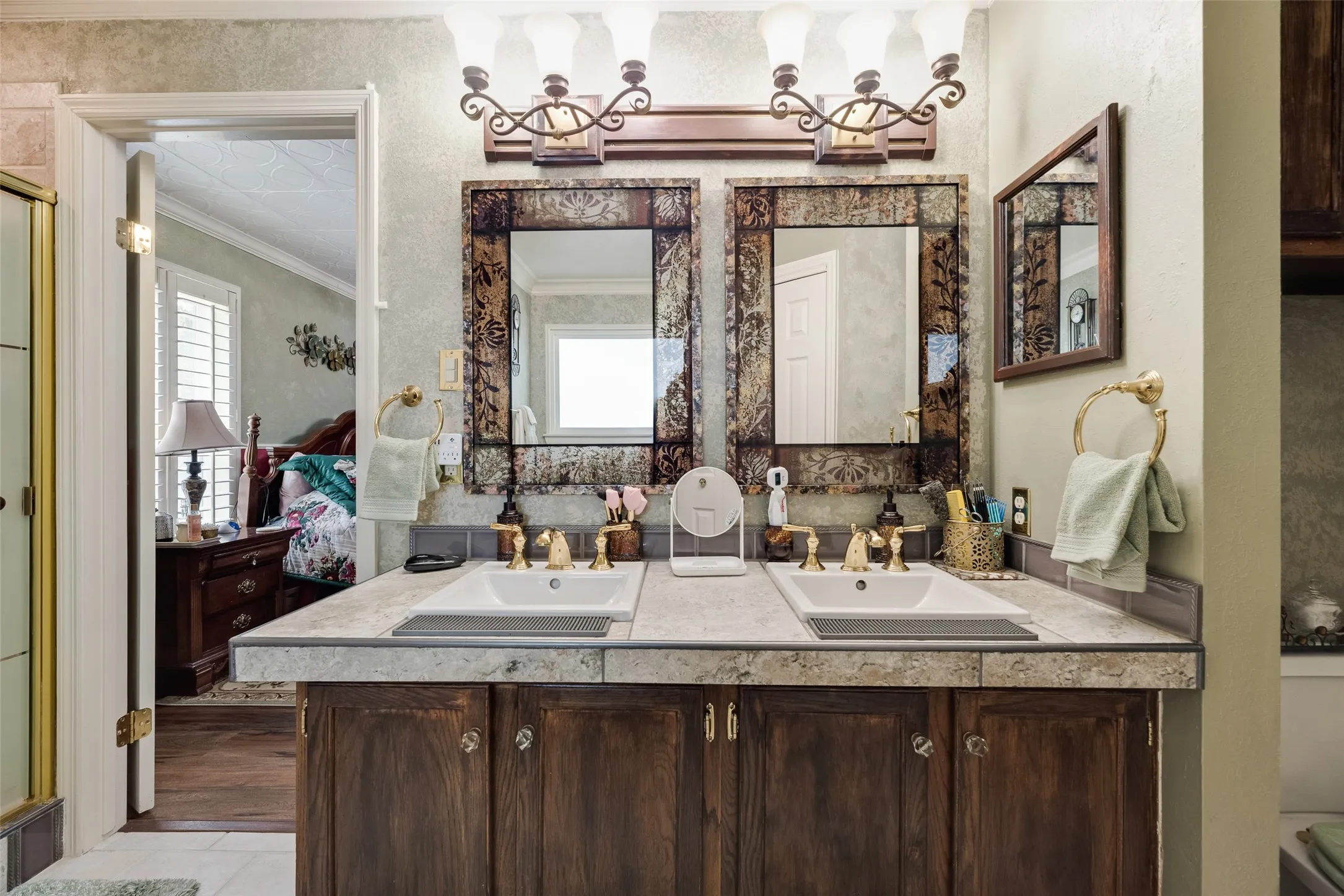 Dual vanity with integrated sinks, dark wood-finish cabinetry, and gold-tone fixtures