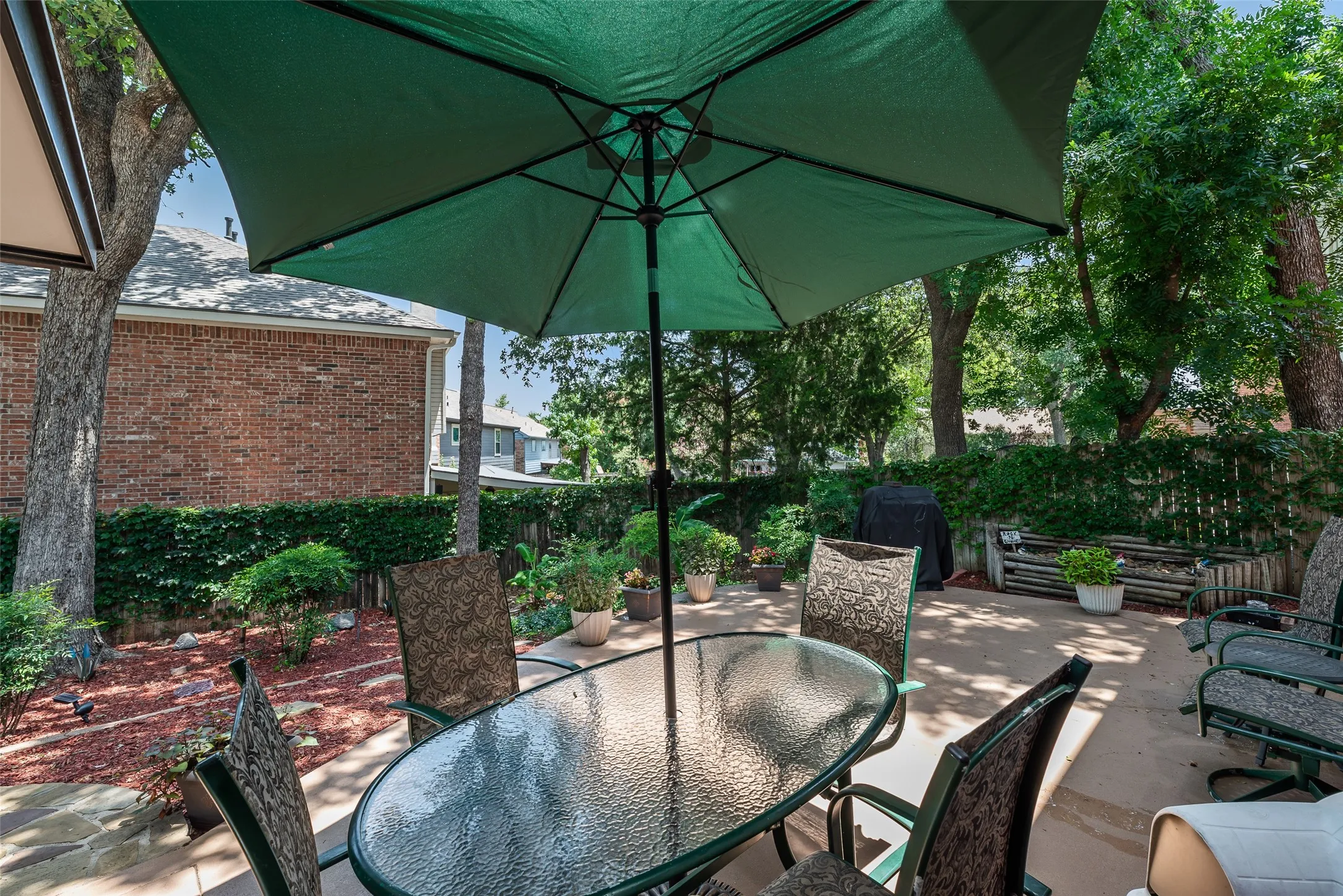 Patio space with concrete surfacing, brick exterior, and mature trees