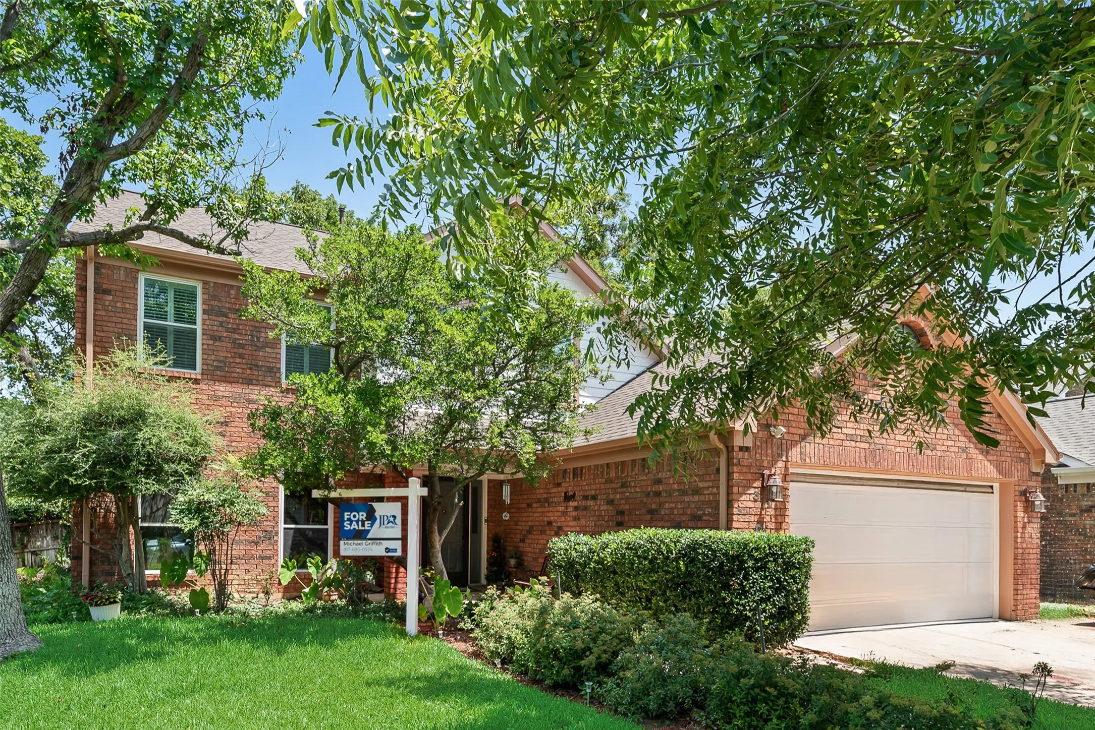 Brick exterior, two-story structure, attached garage, gabled roofline, and established landscaping