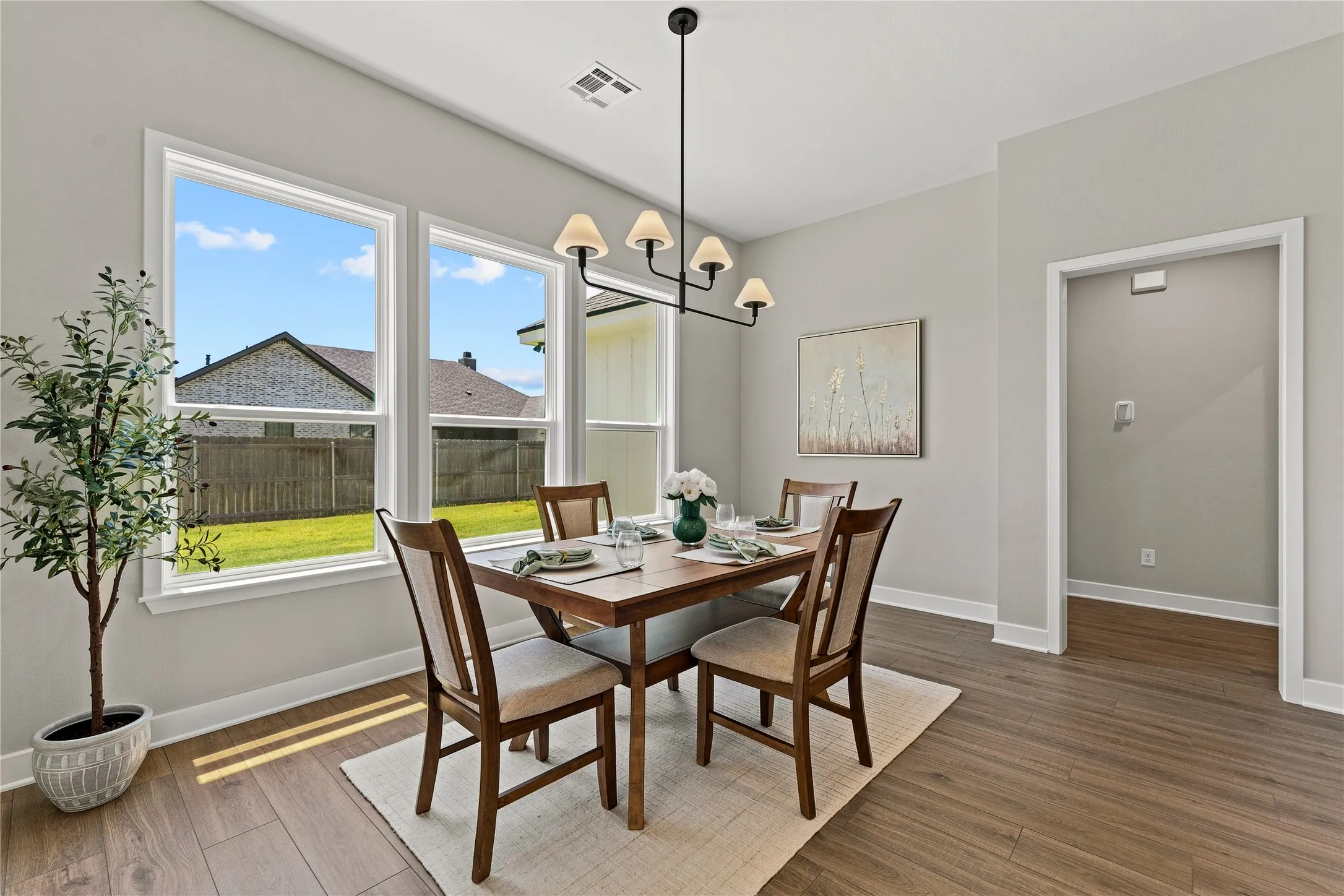Spacious room with wood-finish flooring, light grey walls, and a contemporary chandelier