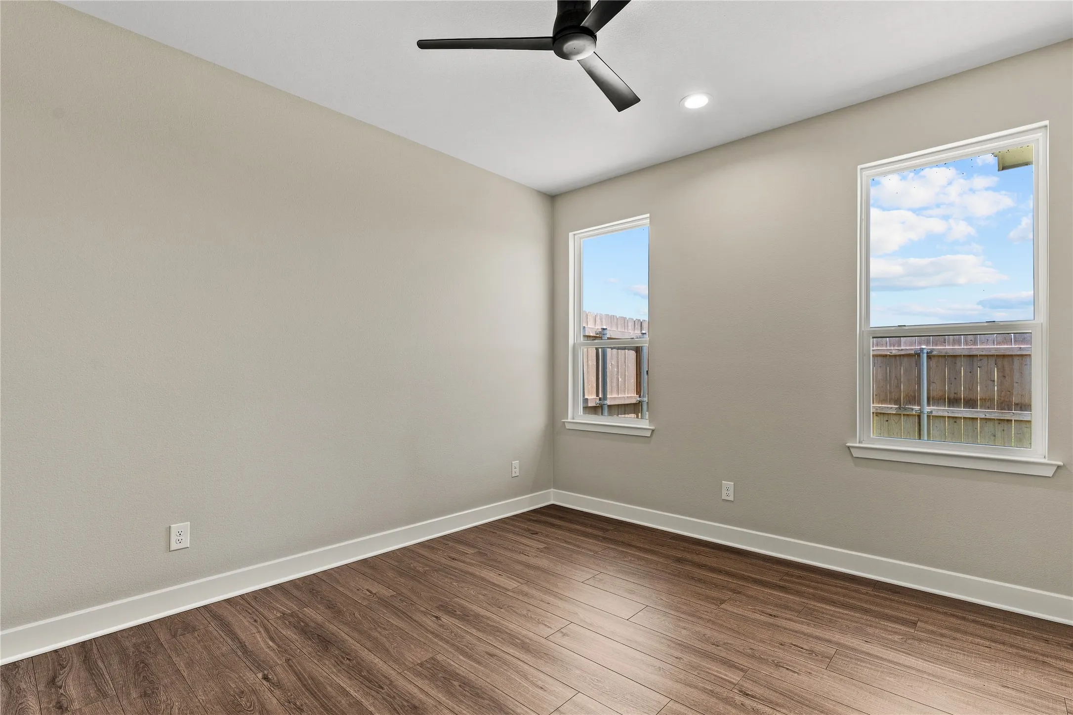 Wood-finish flooring, two windows, ceiling fan, and recessed lighting