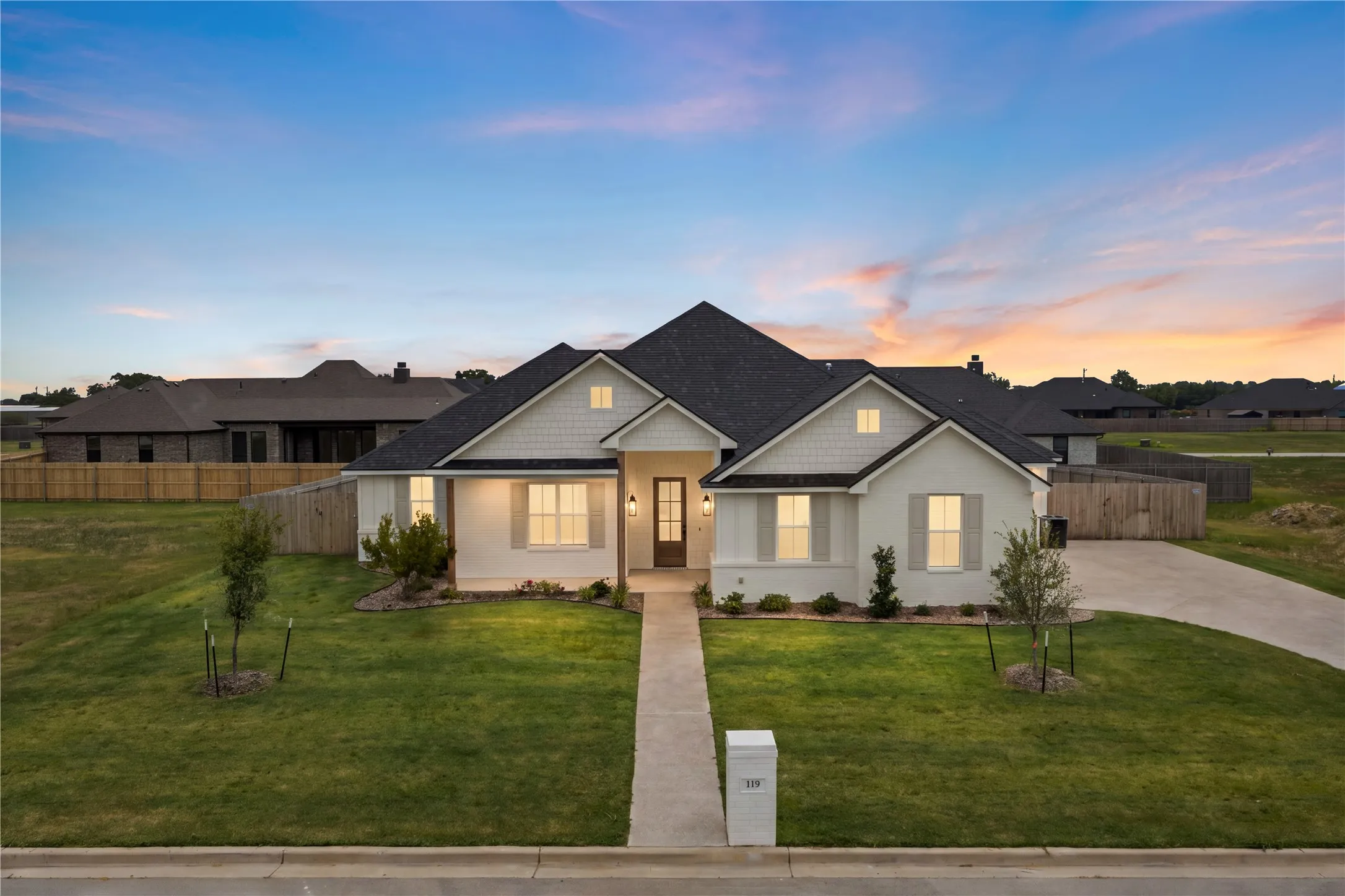 Contemporary ranch-style exterior with white brick, dark shingle roof, and a wood-paneled front door