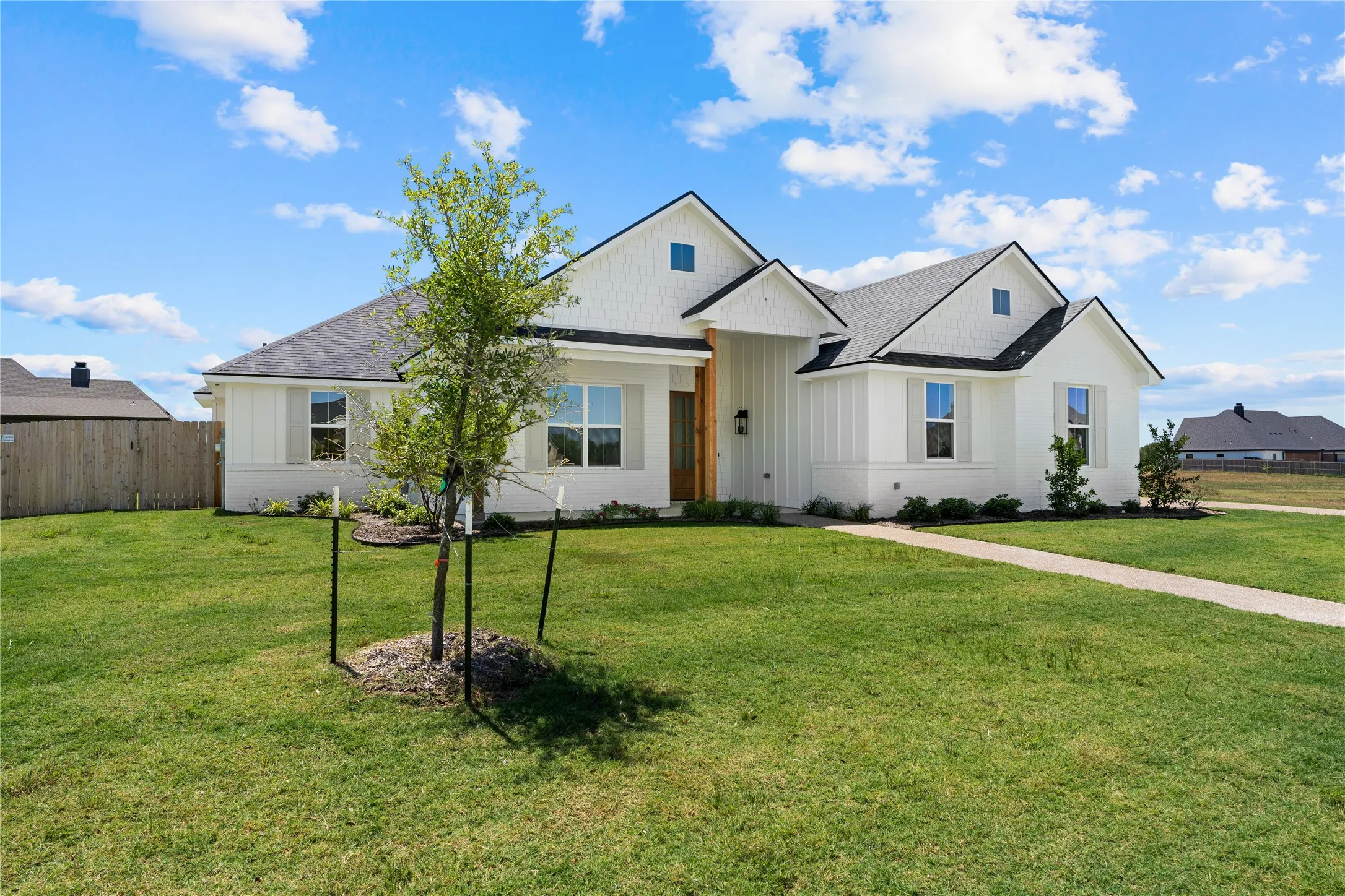 White exterior with dark gabled rooflines, vertical board and batten siding, and a prominent wood-clad entry