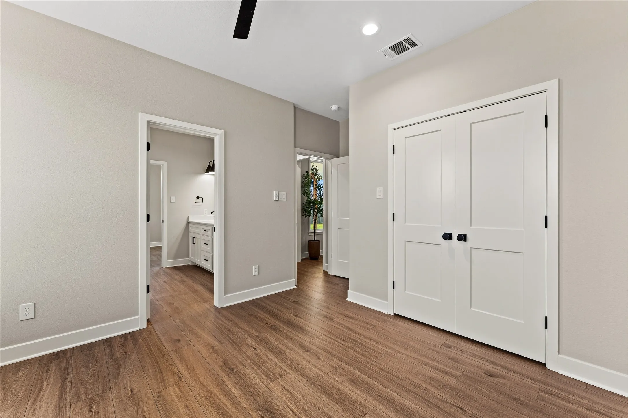 Wood-finish flooring throughout, white interior doors, recessed lighting, and a modern ceiling fan