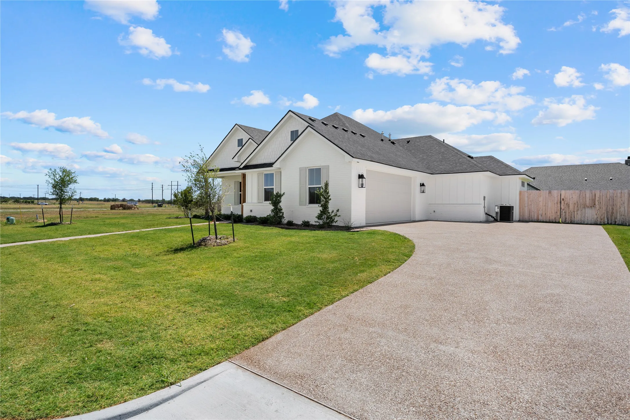 Contemporary single-story residence featuring a white exterior with black trim, a dark shingle roof, and a curved aggregate driveway