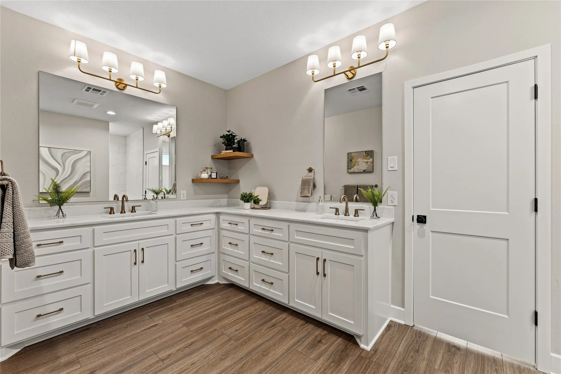 Dual vanity with white cabinetry and integrated sinks, complemented by gold-finish light fixtures