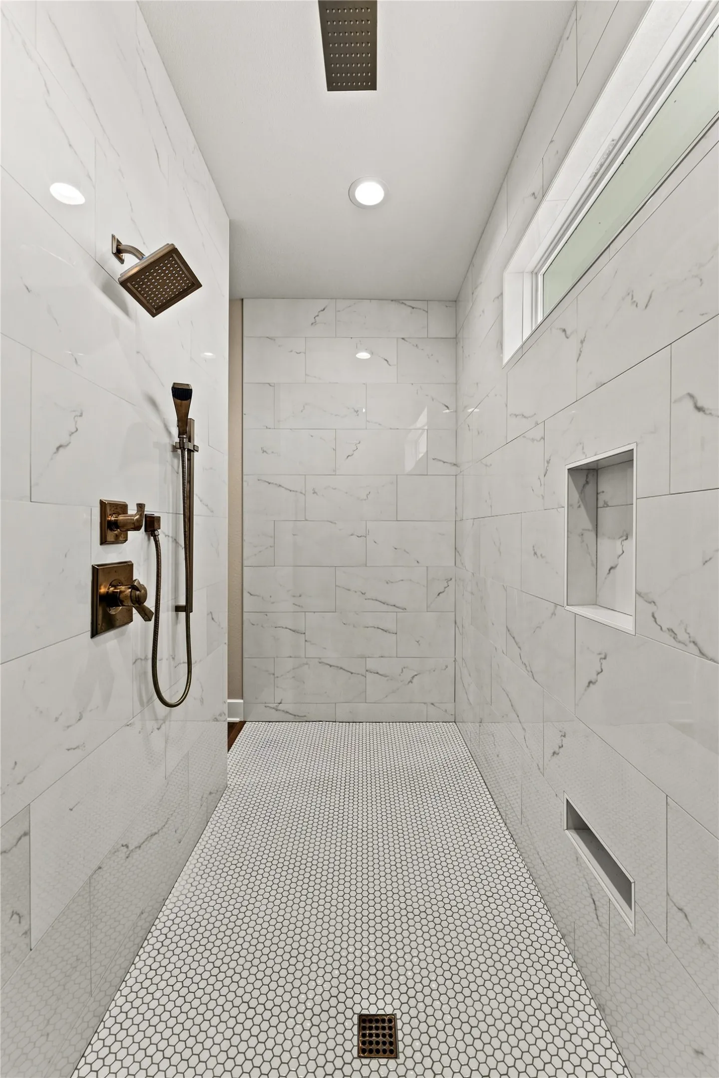 Walk-in shower featuring large format wall tile, a rain shower head, and an additional handheld shower fixture