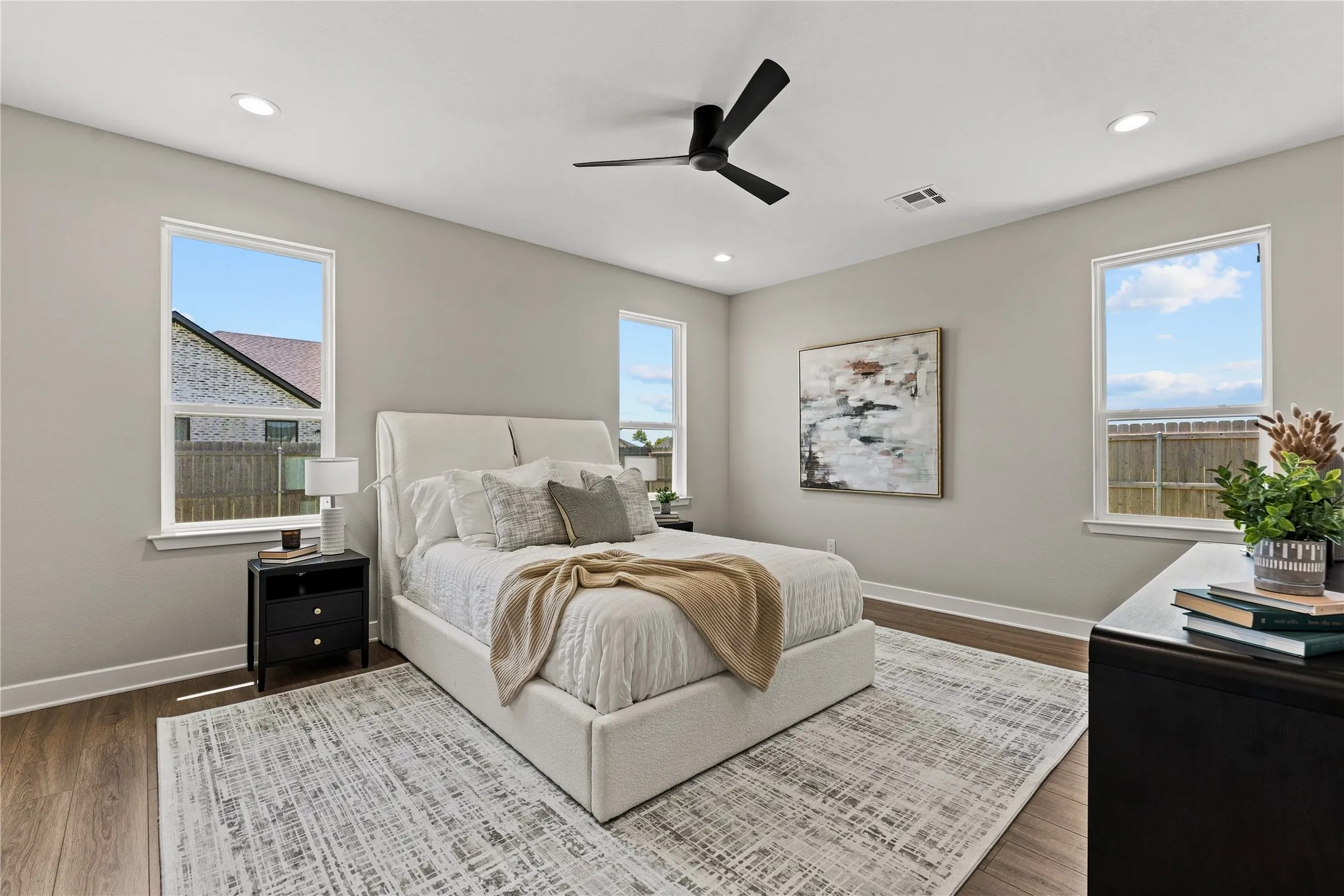 Recessed lighting, wood-finish flooring, ceiling fan, and multiple windows with white trim