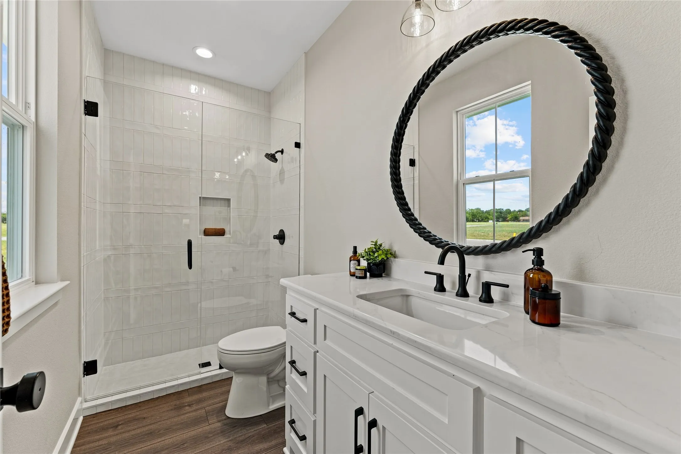 White vanity with a single undermount sink, quartz countertop, and matte black fixtures