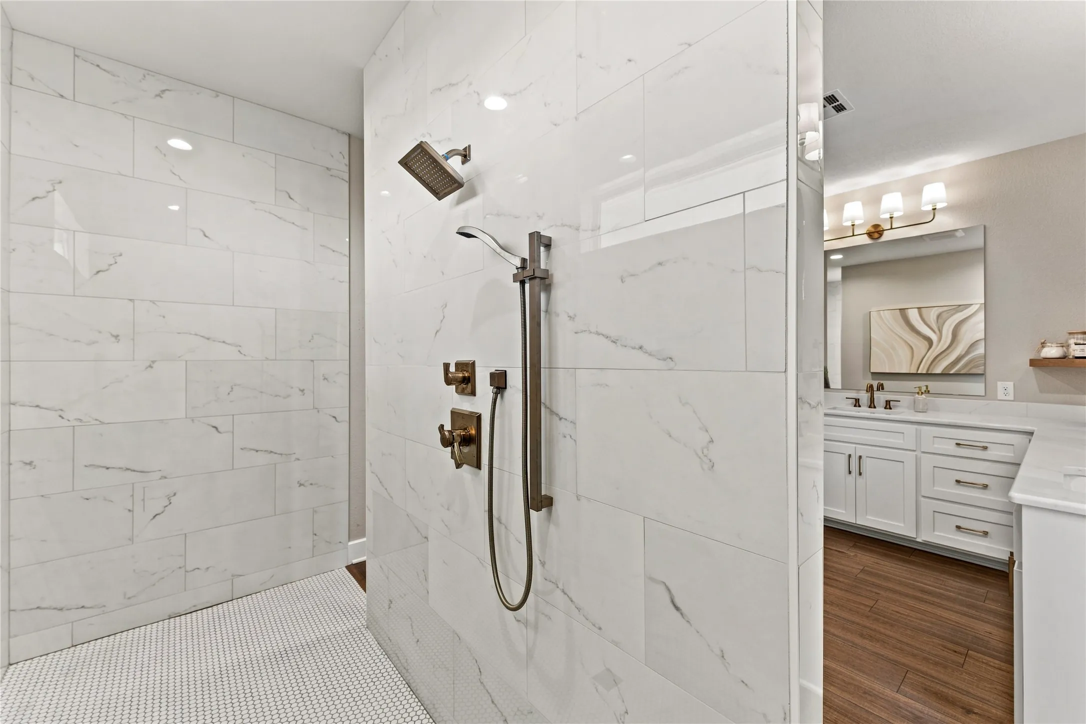 Spacious shower with large format tile walls, mosaic tile flooring, and bronze-finish shower fixtures