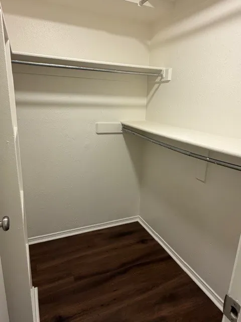 Walk-in closet with integrated shelving, hanging rods, and wood-finish flooring