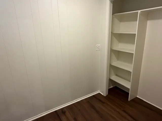 Wood-finish flooring with white wall paneling and built-in shelving