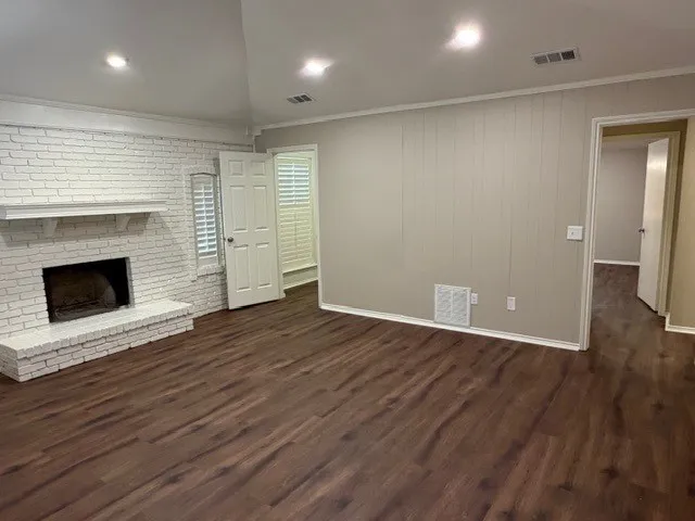 Wood-finish flooring, white-painted brick fireplace with mantel, white plantation shutters, recessed lighting, and a vaulted ceiling