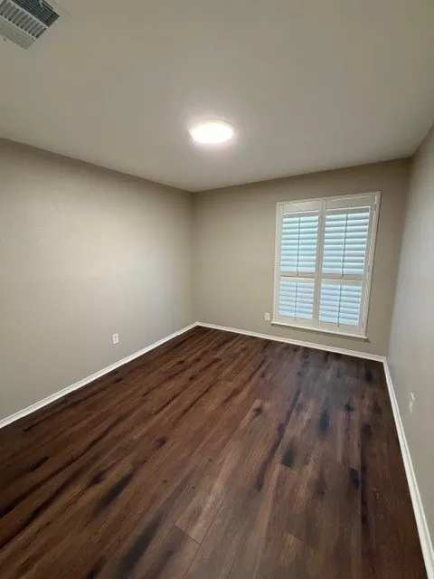 Recessed ceiling light, wood-finish flooring, white window shutters, and neutral wall paint
