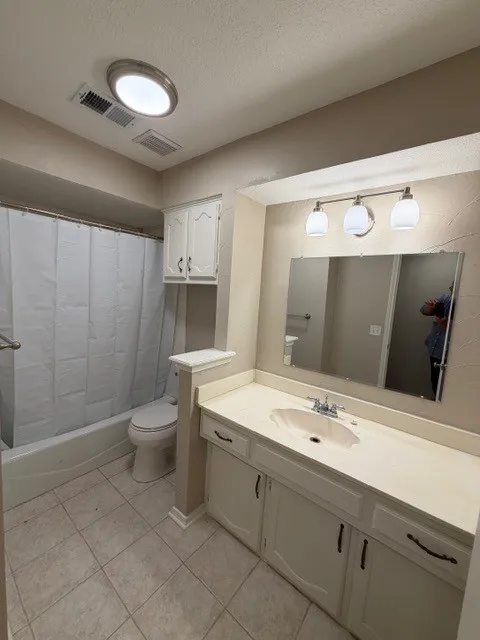 Bathroom featuring a vanity with integrated sink, white cabinetry, overhead lighting, and tiled flooring