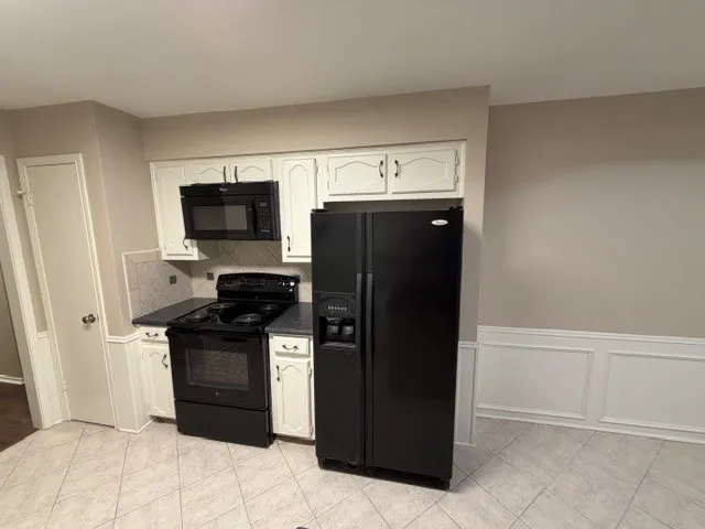 Kitchen featuring white cabinetry, black appliances, tile backsplash, and tile flooring