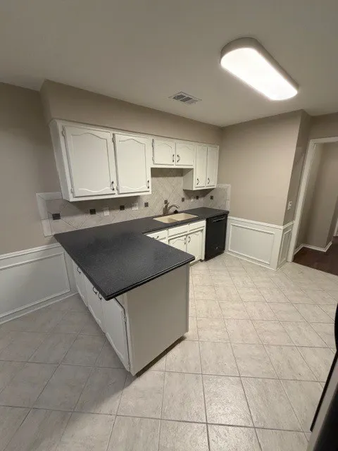Kitchen featuring white cabinetry, dark countertops, a tile backsplash, and tile flooring