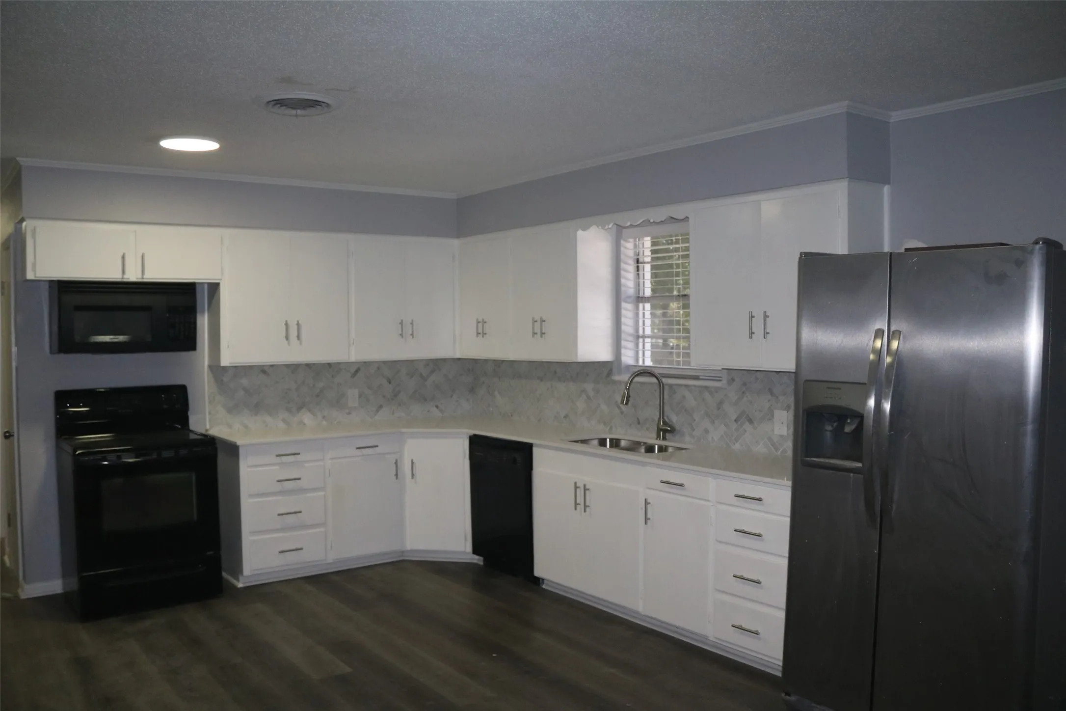 Kitchen featuring wood-finish flooring, white cabinetry, a tile backsplash, and recessed lighting