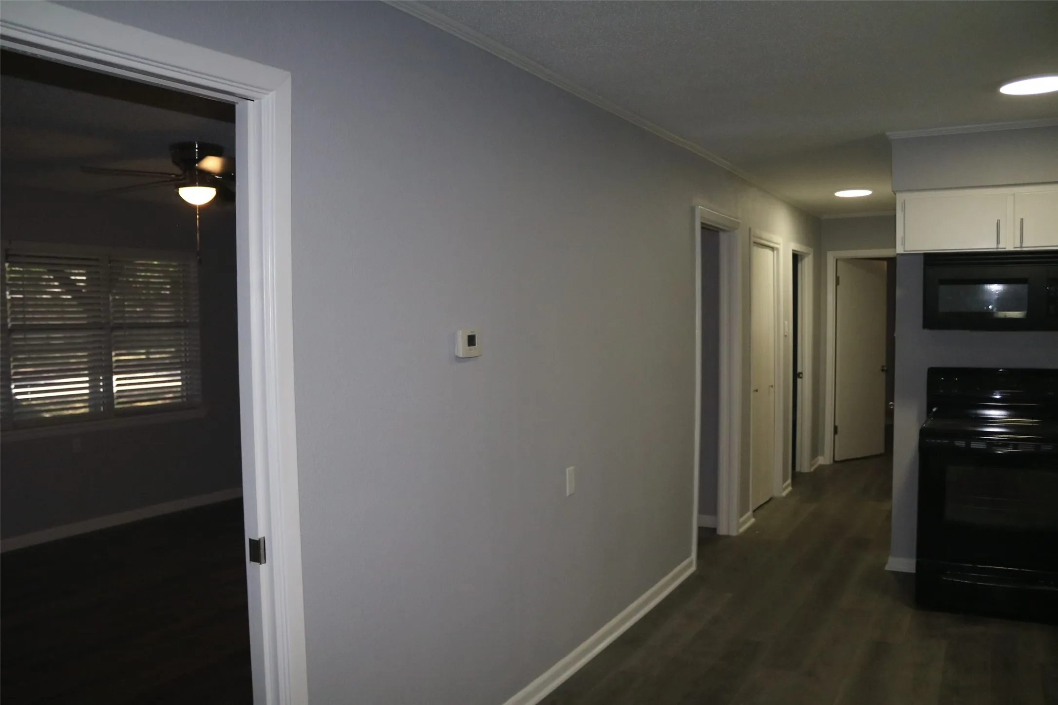 Kitchen with white cabinetry, black appliances, recessed lighting, and wood-finish flooring