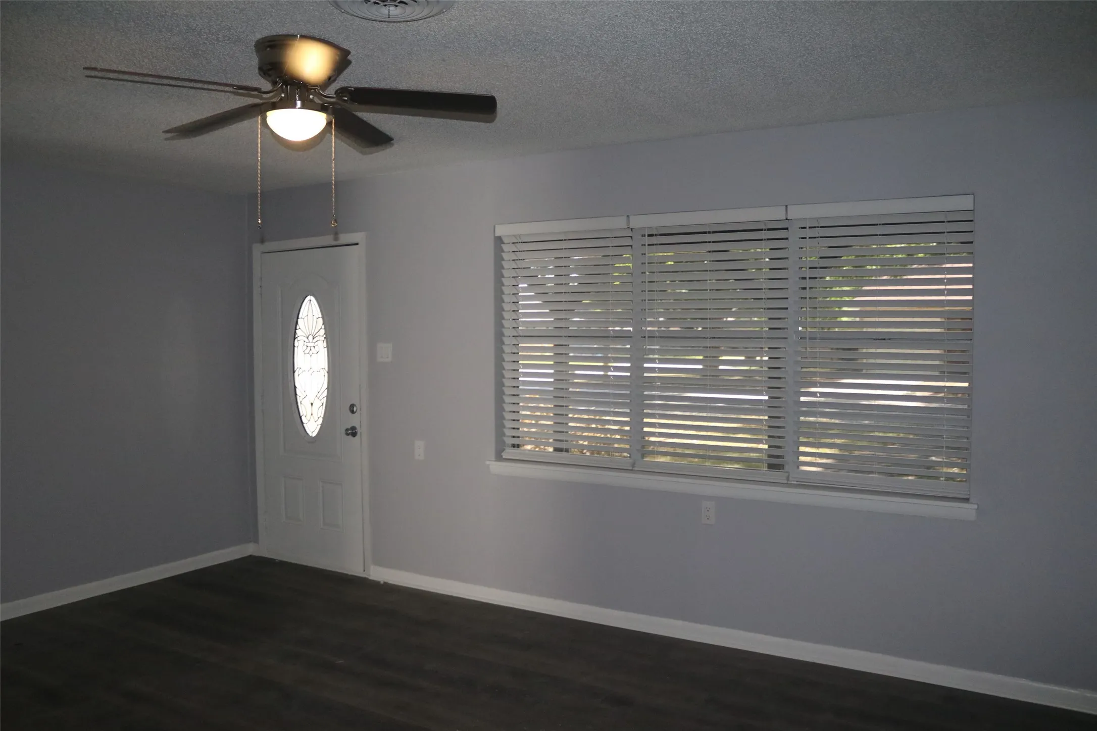 Wood-finish flooring, white trim, and a ceiling fan with integrated lighting