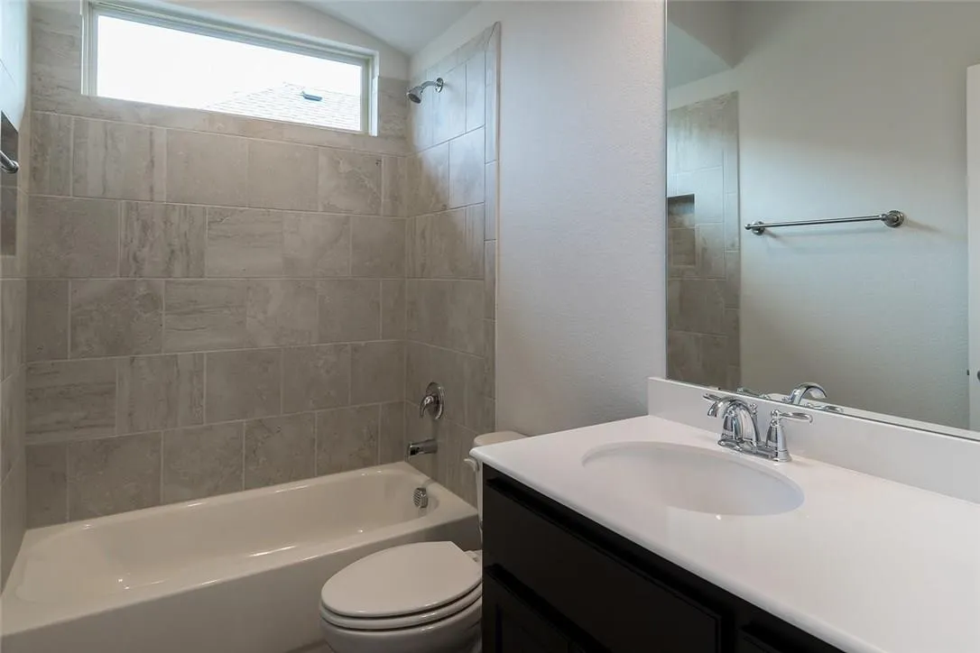 Bathtub with subway tile surround, chrome fixtures, and an overhead transom window