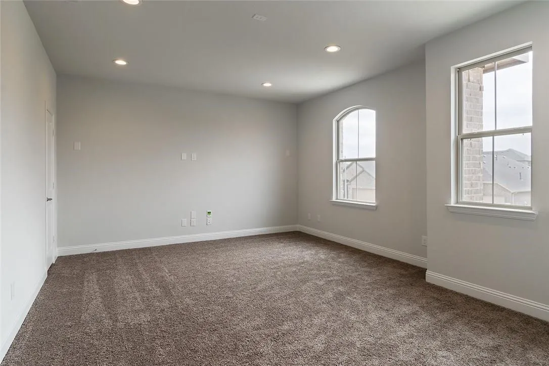 Spacious room featuring neutral paint, recessed lighting, carpet flooring, a classic rectangular window, and an arched window