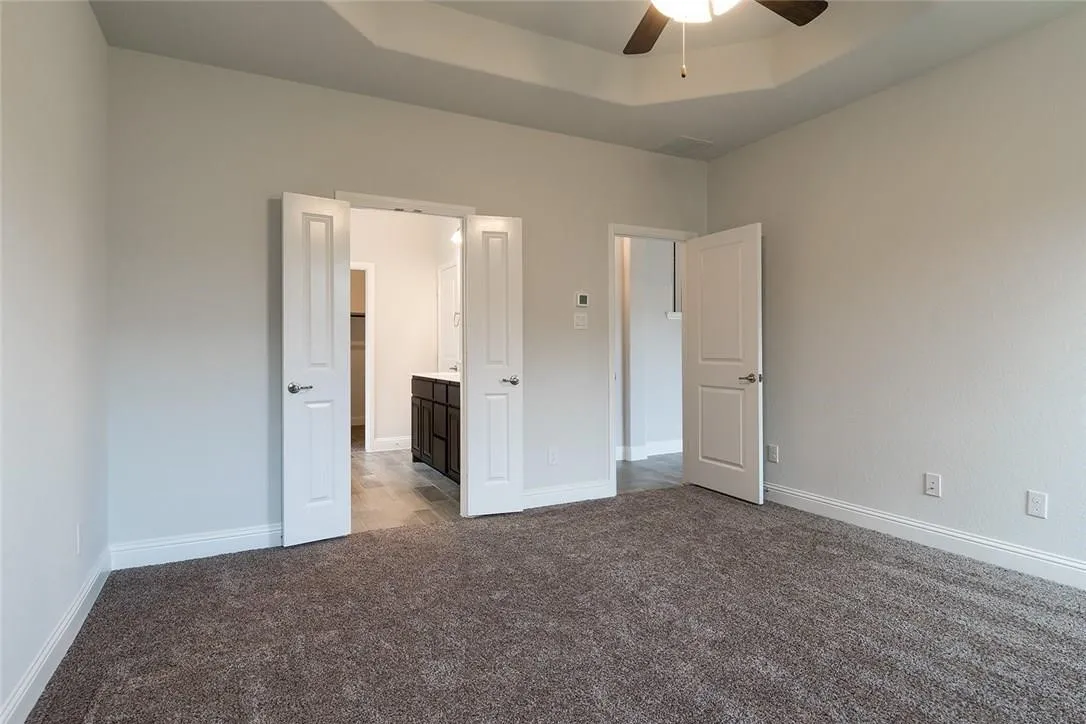 Recessed ceiling with a ceiling fan, carpeted flooring, and white interior doors