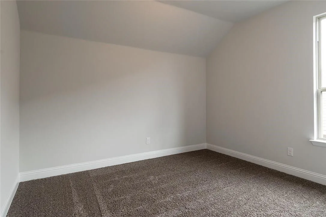 Vaulted ceiling with white paint, plush brown carpeting, white trim, and a double-paned window