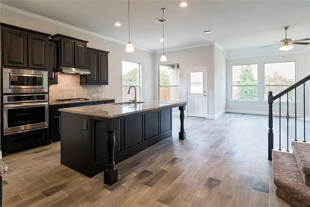Kitchen island with granite countertop, dark wood cabinetry, and stainless steel appliances