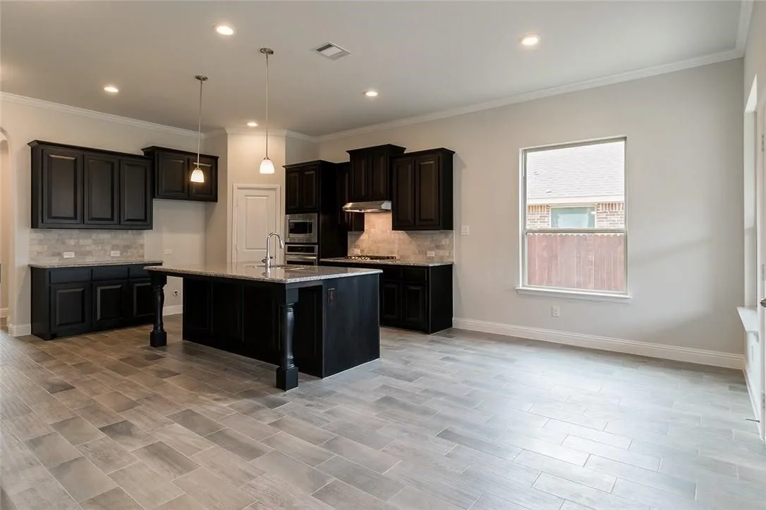 Kitchen featuring dark cabinetry, stone countertops, and a subway tile backsplash
