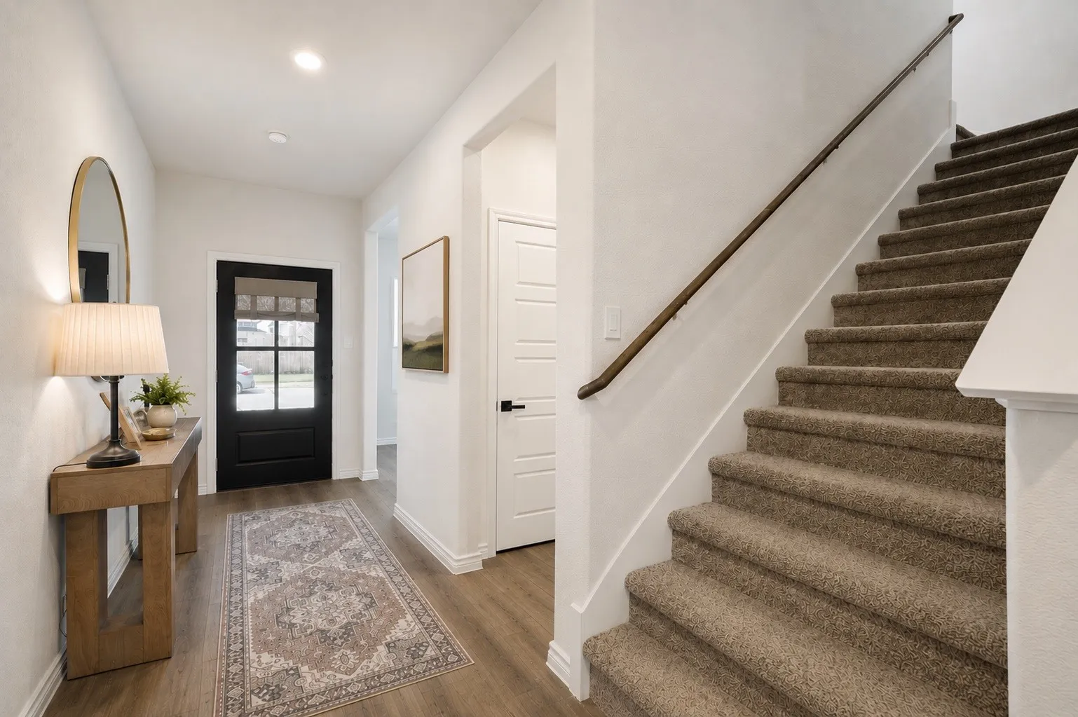 Entryway with wood-finish flooring, a black paneled door with glass inserts, and recessed lighting