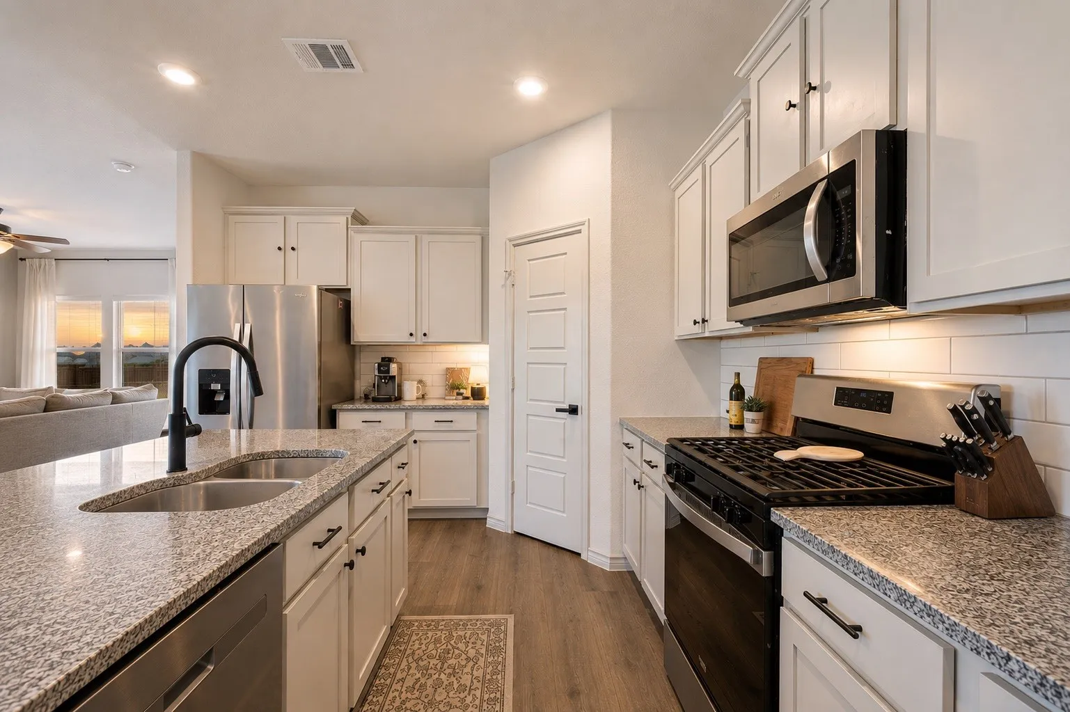Kitchen featuring white cabinetry, granite countertops, stainless steel appliances, a subway tile backsplash, and wood-finish flooring