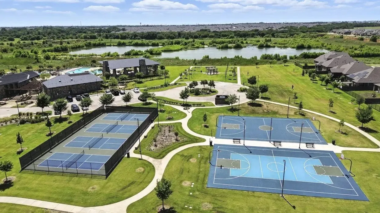 Multiple pickleball courts, two basketball courts, a community building with a pool, and expansive green spaces with natural water features