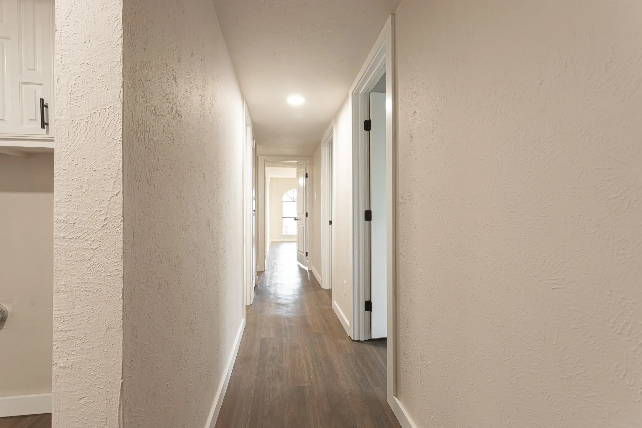 Hallway-Recessed lighting, wood-finish flooring, white built-in cabinetry with black hardware, and textured wall finishes