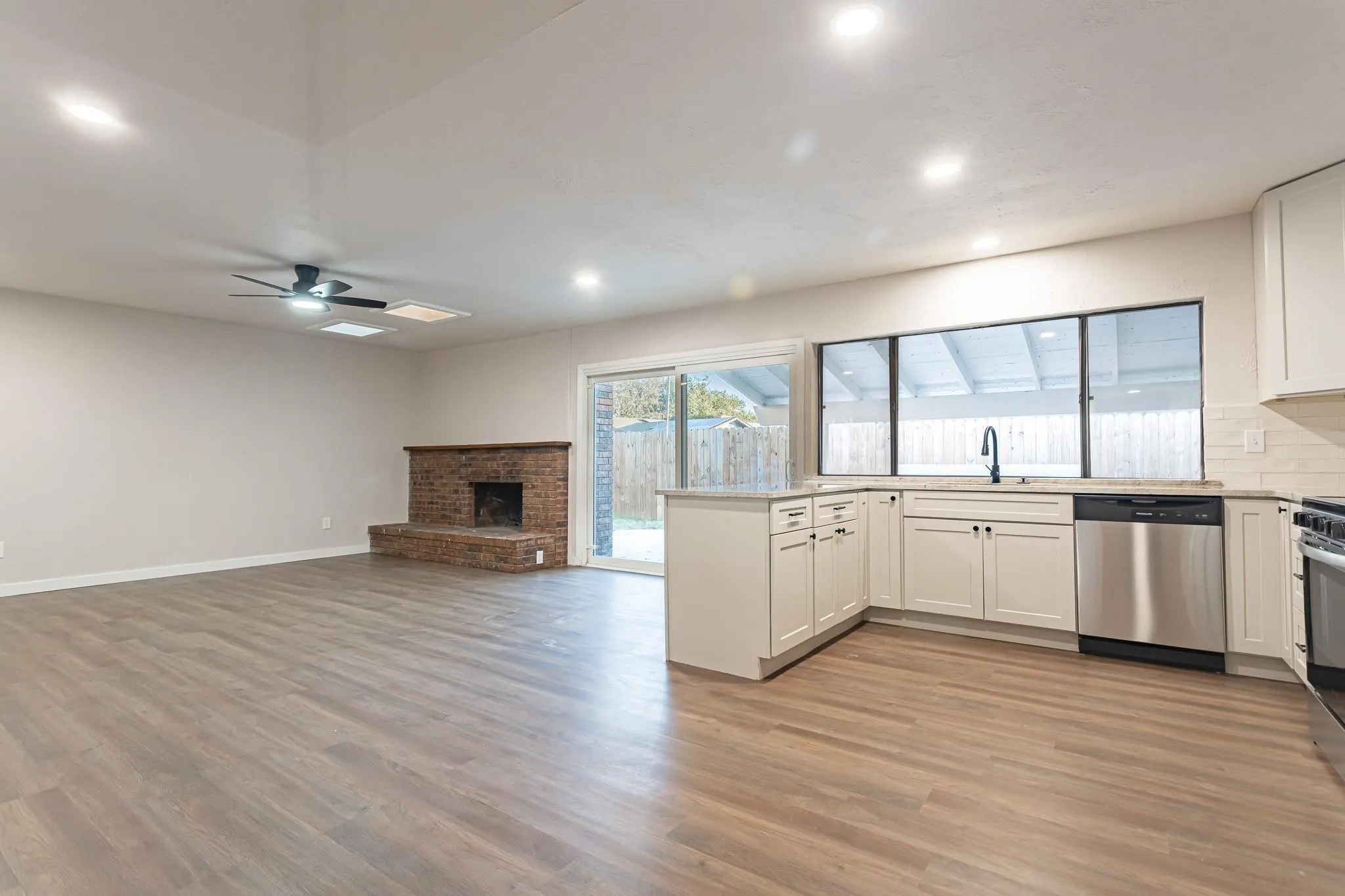 Open-concept living space featuring wood-finish flooring, a brick fireplace, and recessed lighting