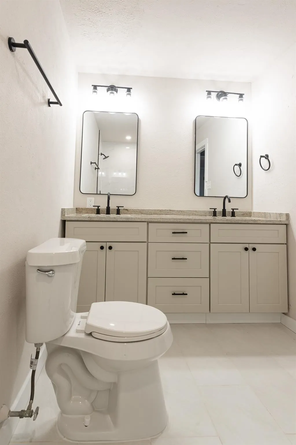 Dual vanity with light-toned cabinetry, two rectangular framed mirrors, and matte black fixtures