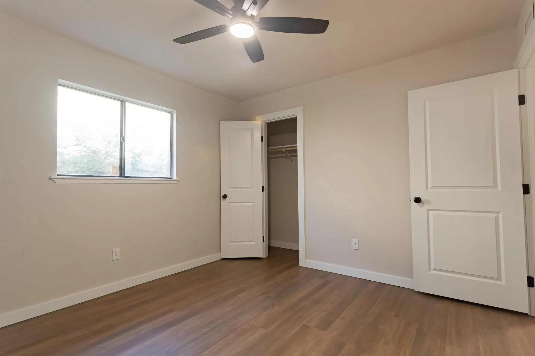 Bedroom 3 Room featuring wood-finish flooring, a ceiling fan with integrated lighting, a window, and a built-in closet with shelving