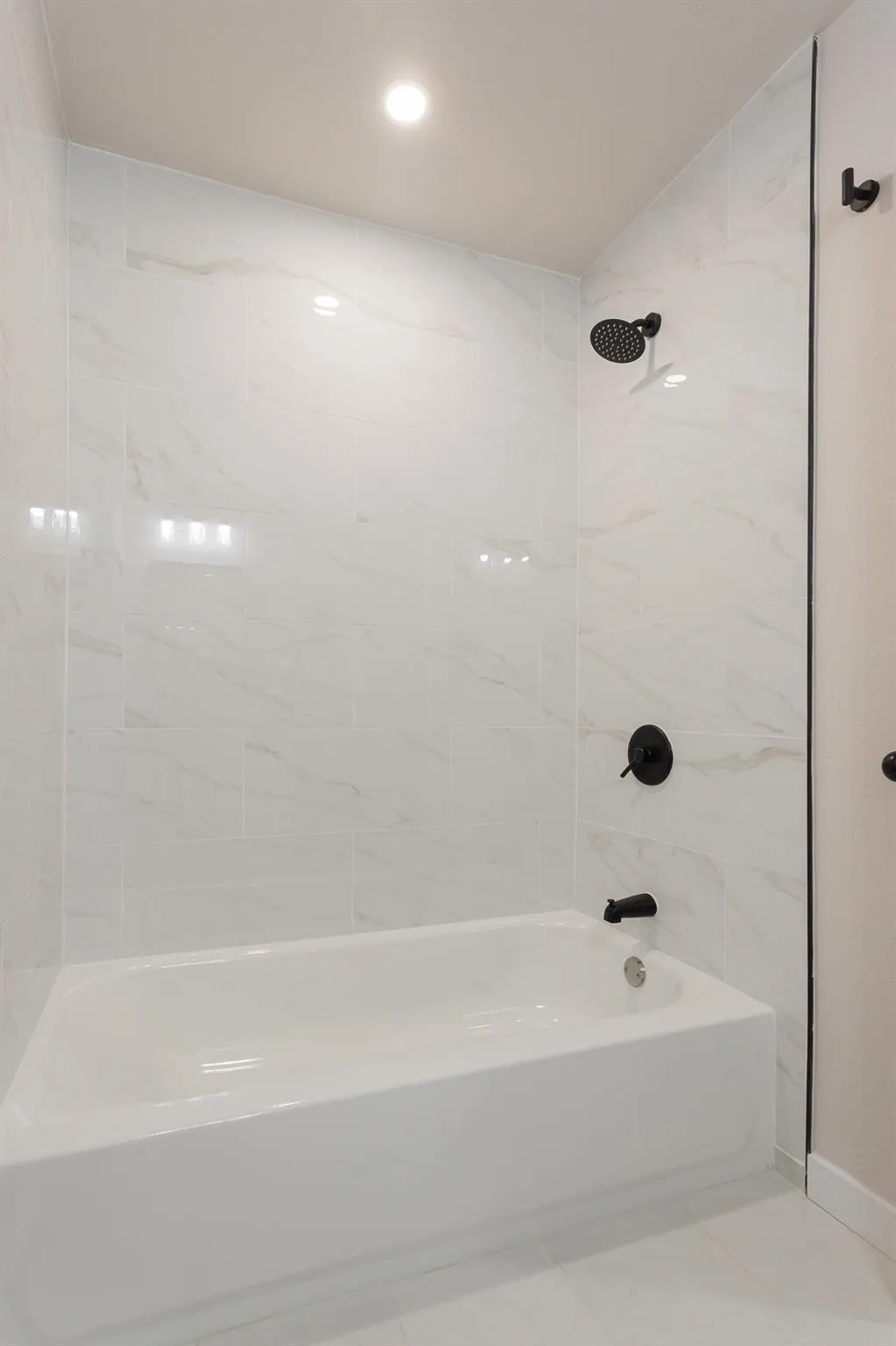 Secondary Bathroom-View 2-Bathtub featuring matte black fixtures, white tile surround, and recessed ceiling lighting