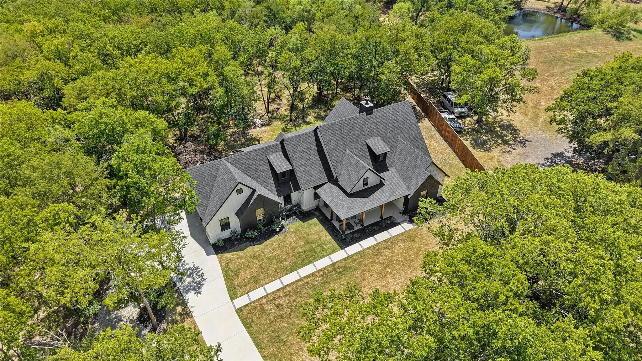 Expansive property featuring a dark shingle roof, multiple dormer windows, and a covered front porch with wood columns