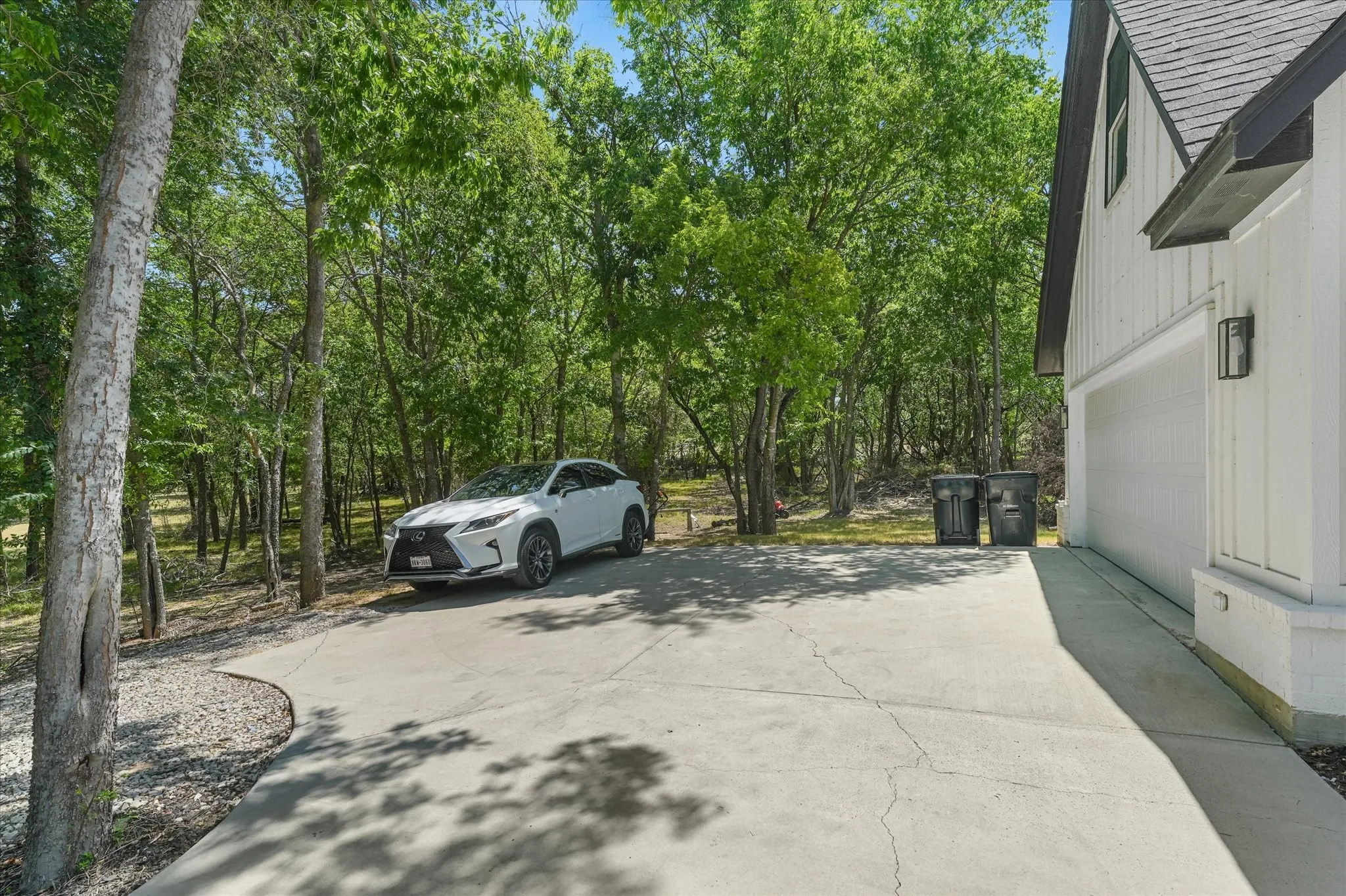 Paved driveway with ample parking and surrounding mature trees