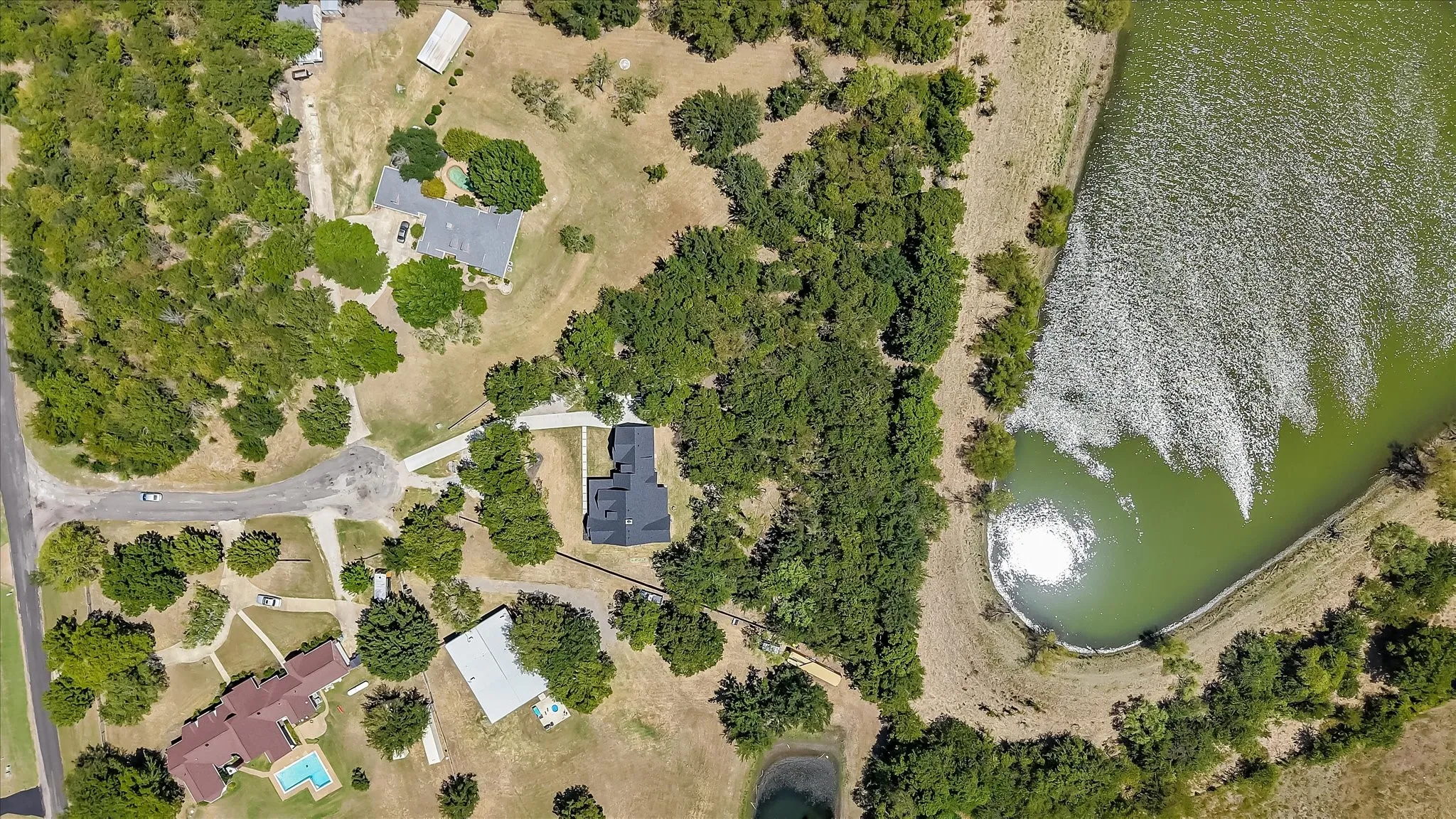 Expansive property featuring a large body of water, mature tree coverage, and multiple residential structures
